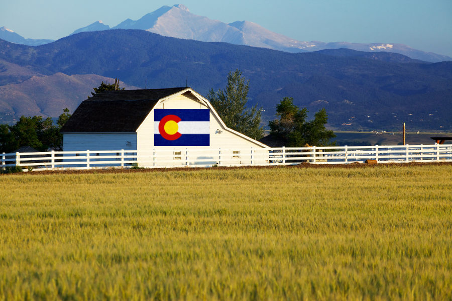 Johnstown CO mortgage broker - Barn in front of the mountains with a Colorado flag