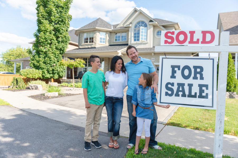 seller concessions - Family standing in front of house with sold sign