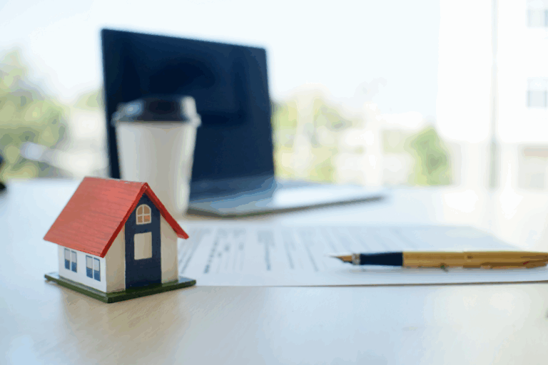 Mortgage Terms - Small wooden house next to a pen and paperwork on top of the desk.